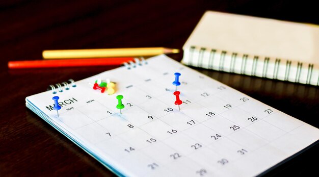 White desk calendar on dark wooden table planning concept