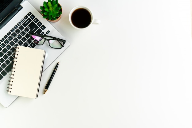 White desk office with laptop, notebook and other work supplies with cup of coffee. Top view ,copy space, flat lay.