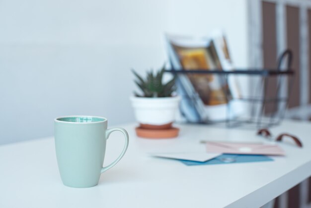 Tavolo scrivania bianco con copia spazio, forniture e tazza da caffè. vista frontale dell'area di lavoro e copia dello spazio.