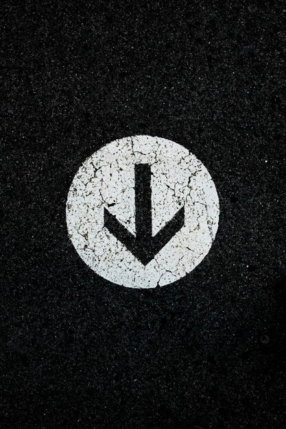 Photo white directional arrow on a black floor