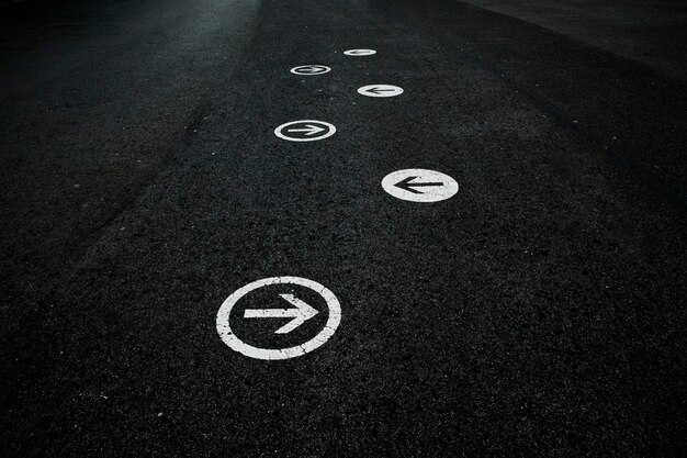 Photo white directional arrows painted on a black floor