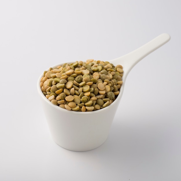 White dish cup full of green lentil. isolated on white.