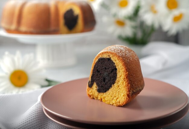 On a white dish, a round cupcake, round with a hole, sprinkled with powdered sugar