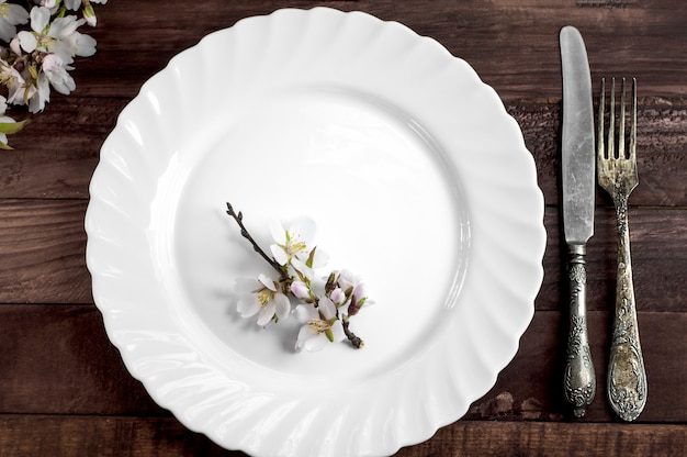 White dish with iron cutlery on a brown wooden surface