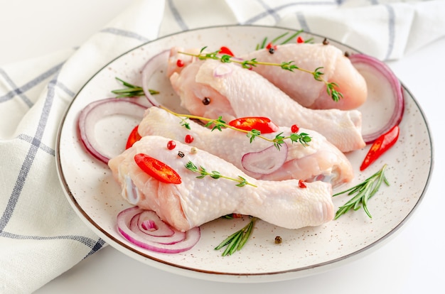 White dish with spicy marinated chicken legs or drumsticks. Raw meat and cooking concept.