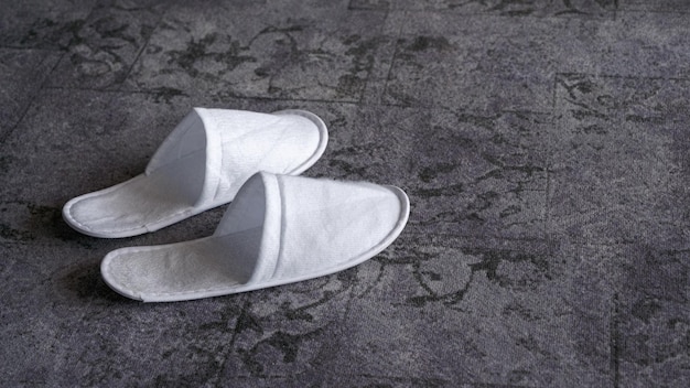 Photo white disposable slippers resting on a patterned hotel carpet