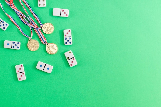 White dominoes with colorful dots and winner medals on a green\
background top view board game