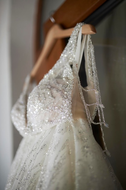 朝の花嫁のホテルの準備でドアにぶら下がっている花嫁の白いドレス