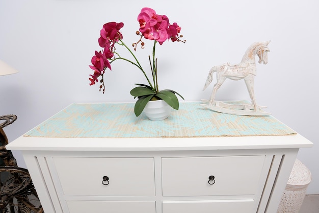 A white dresser with a white horse and a vase of flowers on it.