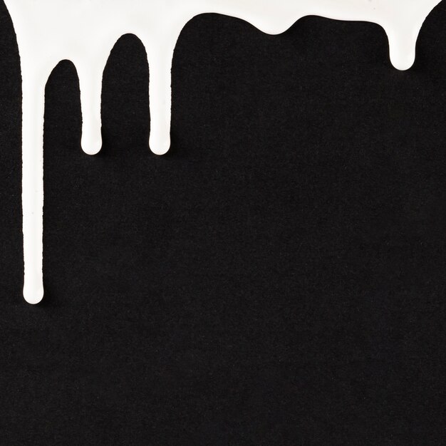 White dripping paint on black background