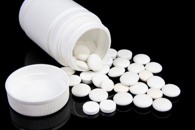 White drugs and plastic box for pills on black table