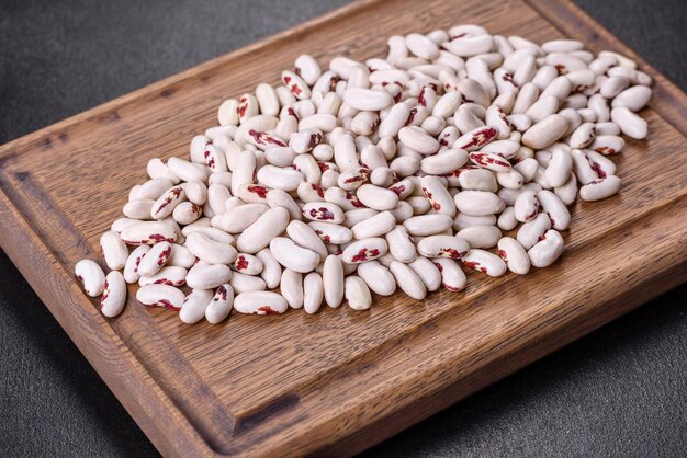 Photo white dry raw beans on a dark concrete background