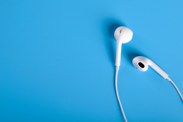 White earphones on blue table with copyspace