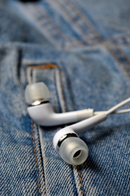 White earphones over a denim jacket. close-up.