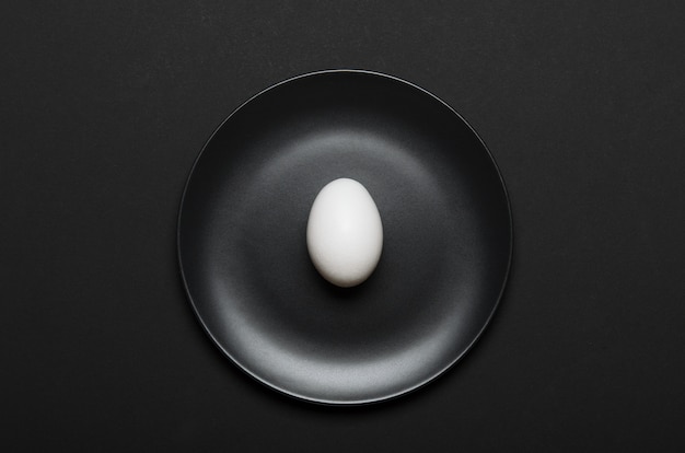 White egg on black plate on black.