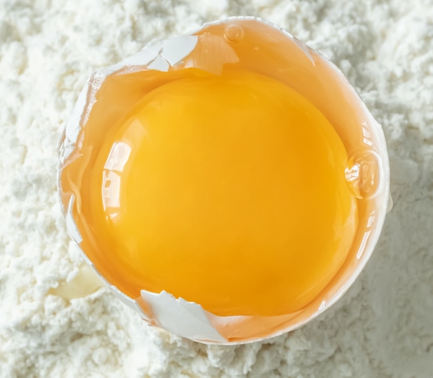 White egg and egg yolk on flour