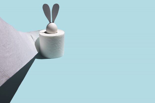 White egg with hare ears in a roll of toilet paper.