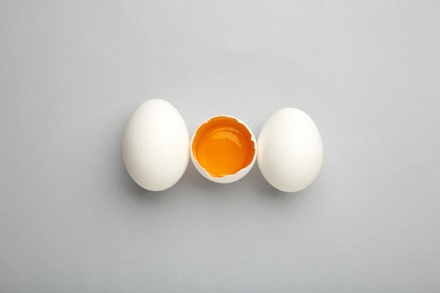 white eggs and egg yolk on the grey background.