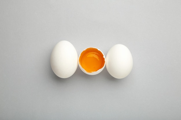 White eggs and egg yolk on the grey background.