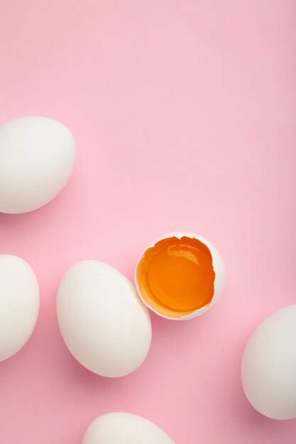 White eggs and egg yolk on the pink wall. Easter concept. 