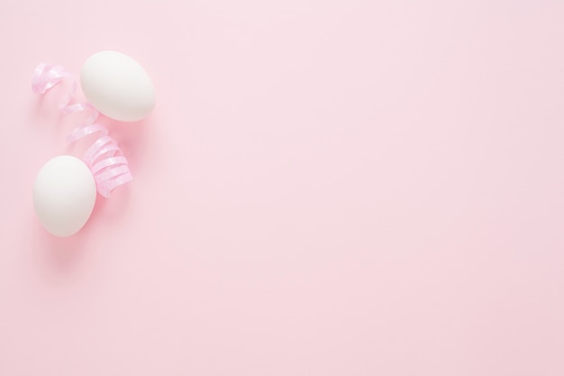 White eggs on a pink background with copy space