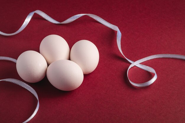 White eggs with fabric ribbon on red paper