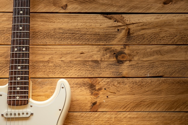 White electric guitar on a brown wooden table, with copy space.