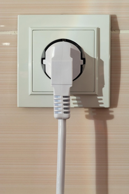 White electric power sockets on wall background with plugged electric plug