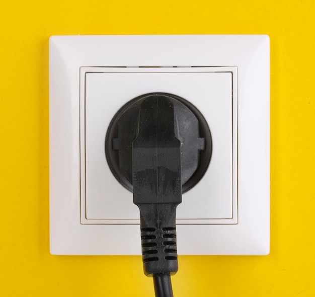 Photo white electric socket with plug on the wall