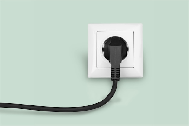 White electrical plug in the electric socket on a wall