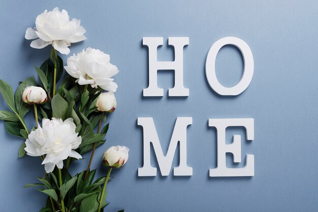 White elegant peonies on the blue wall with word home