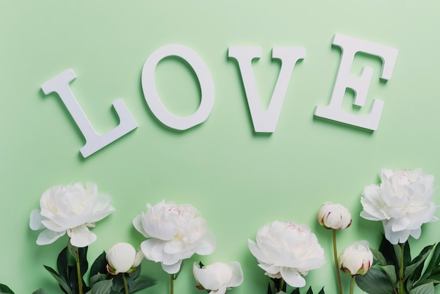 White elegant peonies on the green wall with word love