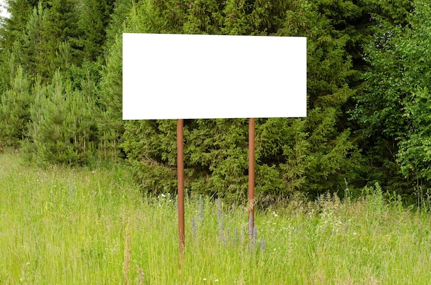 A white empty billboard in the forest among the trees Posting information in a public park or drawing attention to environmental issues Summer copy space