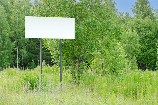 A white empty billboard in the forest among the trees Posting information in a public park or drawing attention to environmental issues Summer copy space