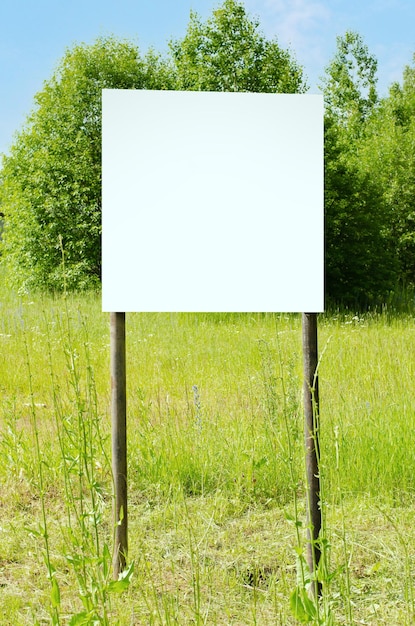 A white empty billboard in the forest among the trees Posting information in a public park or drawing attention to environmental issues Summer copy space