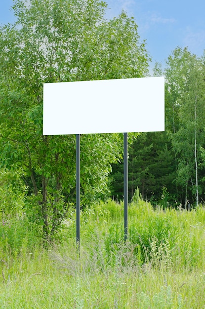 A white empty billboard in the forest among the trees Posting information in a public park or drawing attention to environmental issues Summer copy space