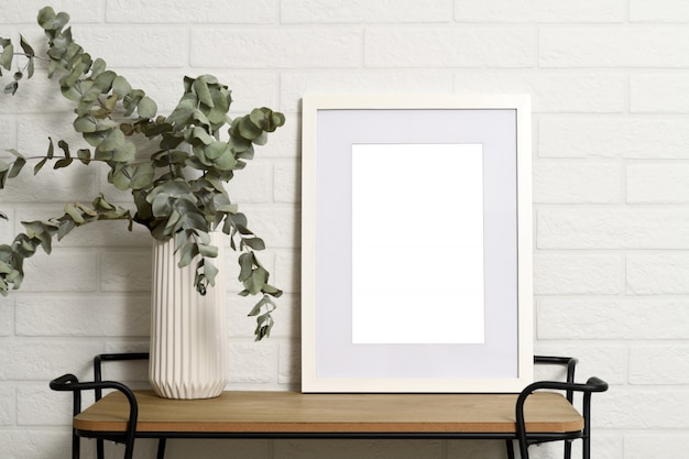 White empty frame on shelf with plant in vase