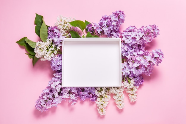 White empty gift box decorated with lilac flowers on pink background