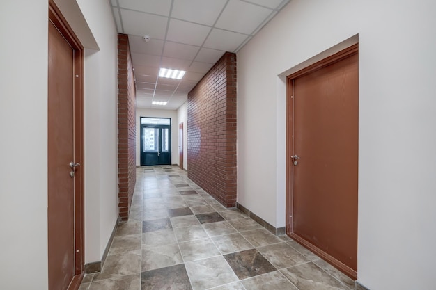 Photo white empty long corridor with red brick walls and doors in interior of modern apartments or office