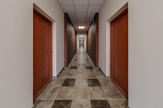 Белый пустой длинный коридор с красными кирпичными стенами для кабинета в интерьере офиса или клиники современных квартир