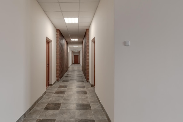 White empty long corridor with red brick walls for room office in interior of modern apartments office or clinic