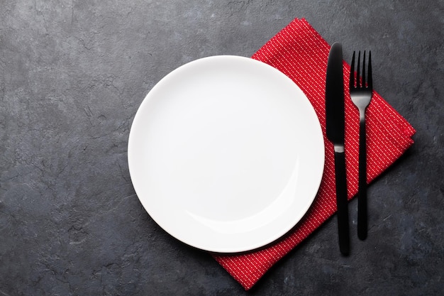 White empty plate fork knife and napkin on stone table Top view flat lay with space for your meal