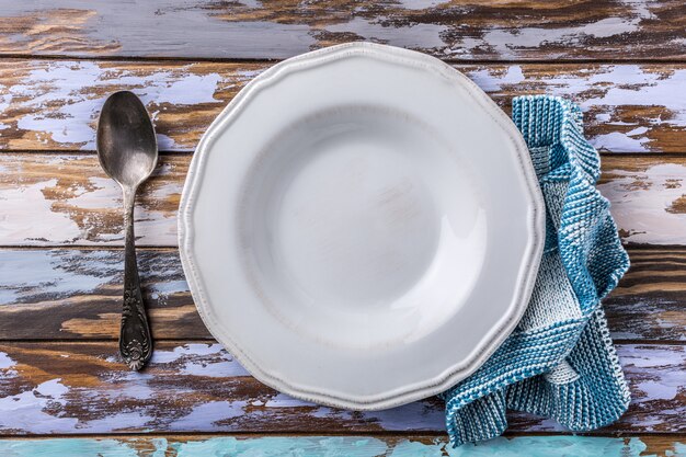 White empty plate on old wooden table, background concept blue