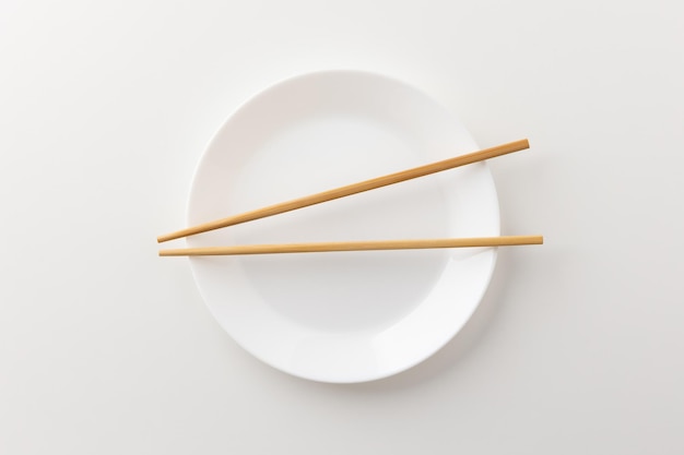 Белая пустая тарелка с палочками для еды на тарелке