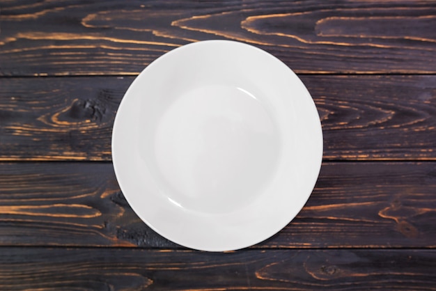 White empty plate on a wooden surface. 