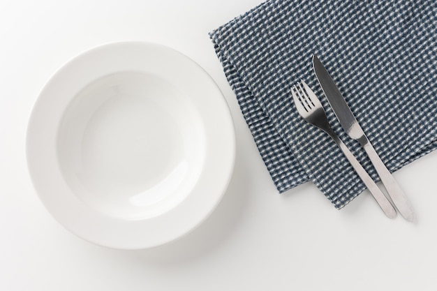 White empty plates set on the table with knives and forks and tablecloths. Ready to eat