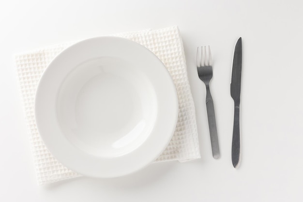 Piatti vuoti bianchi sul tavolo con coltelli, forchette e tovaglie. pronto a mangiare