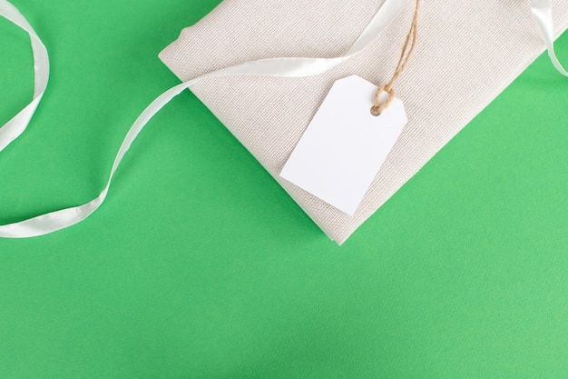 White empty tag on clothes Mockup of a price tag label on a fabric product Green background