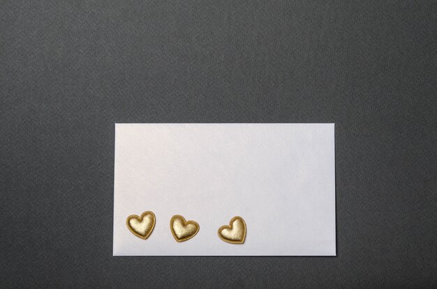 White envelope and golden hearts on a black top