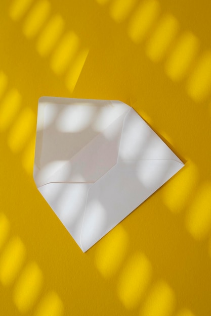Белый конверт под солнечным светом на желтом фоне Вид сверху на плоскую планировку